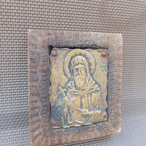 Old brass icon of Saint Anthony in carved wooden frame, used