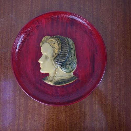 Decorative wall plate used with embossed female profile on burgundy background
