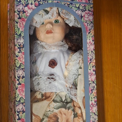 Porcelain collectible doll with brown curly hair and vintage dress, new