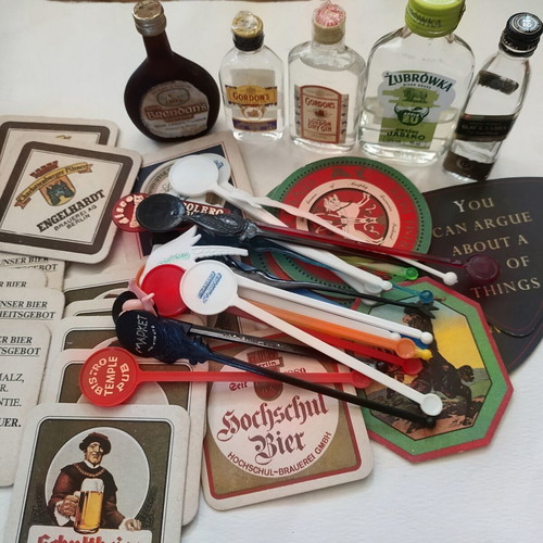 Vintage bar collection with mini liquor bottles, coasters, and stirrers
