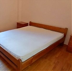 Κρεβάτι διπλό ξύλινο με δύο κομοδίνα χωρίς στρώμα. Παίρνει στρώμα περίπου 1,35×1,95 μ.