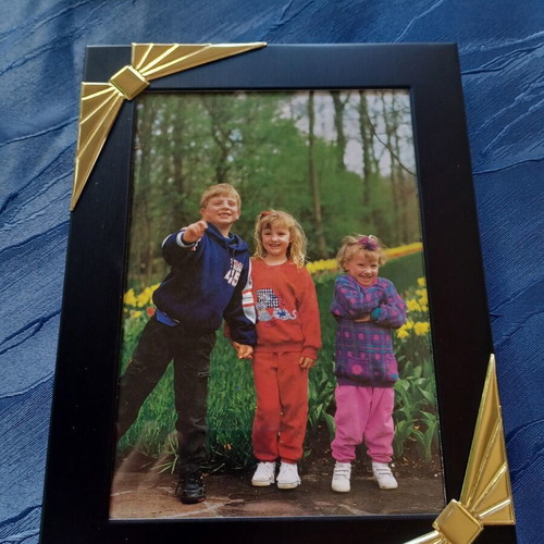 Black photo frame with golden decorative bows used