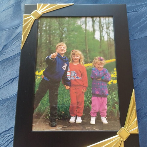 Black photo frame with golden decorative bows used