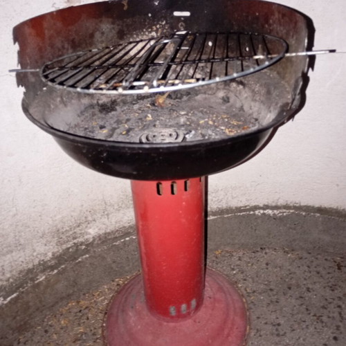 Portable vintage charcoal barbecue with red central leg, used