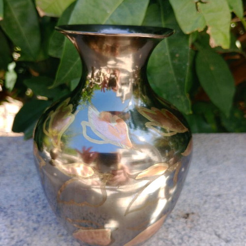 Intricately enameled brass vase with flowers.