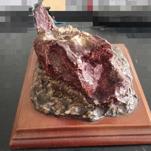 Decorative used piece with red mineral stone on wooden base