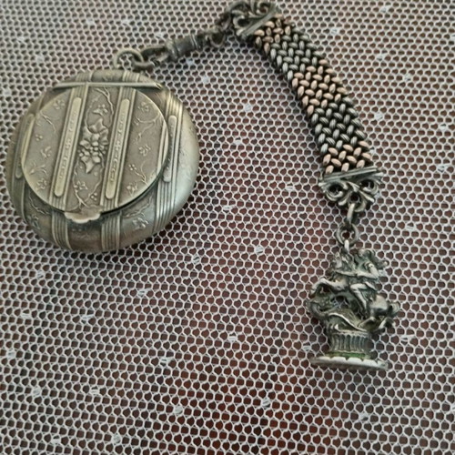 Silver powder compact used, 1880 era with chain and embossed figures