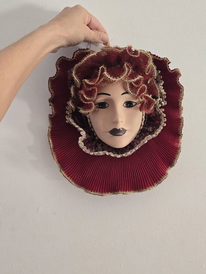 Decorative porcelain wall mask used with fabric hat in burgundy