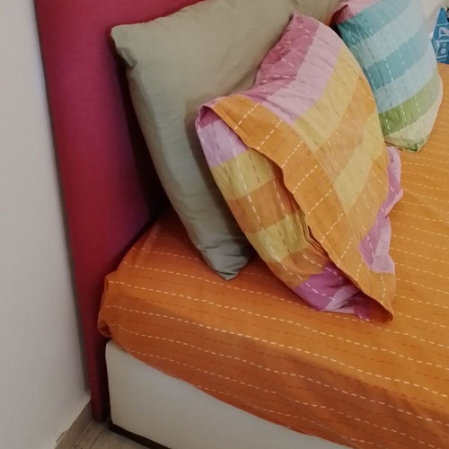 Double bed with fuchsia headboard, wooden support boxes and mattress