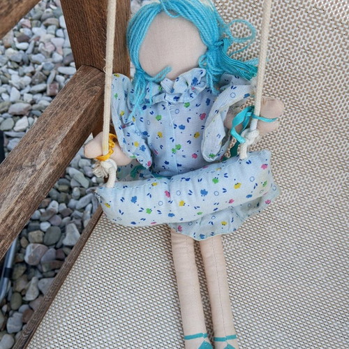 Cloth doll used, hanging in a swing