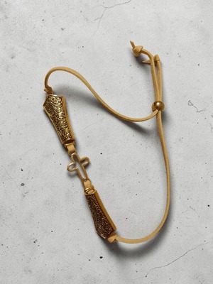 Handmade bracelet with cross and large gold embossed elements on leather cord
