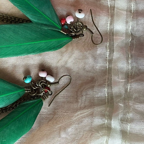 Handmade earrings used with green feathers and multicolored beads