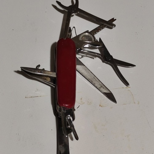 Multitool pocket knife used with red handle and multiple foldable tools