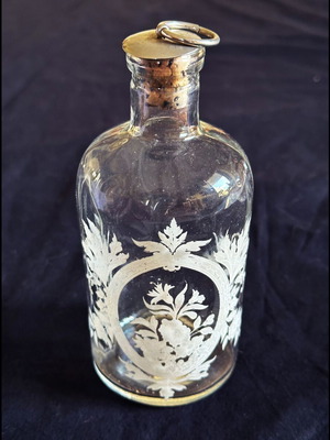Glass apothecary bottle used with etched floral design