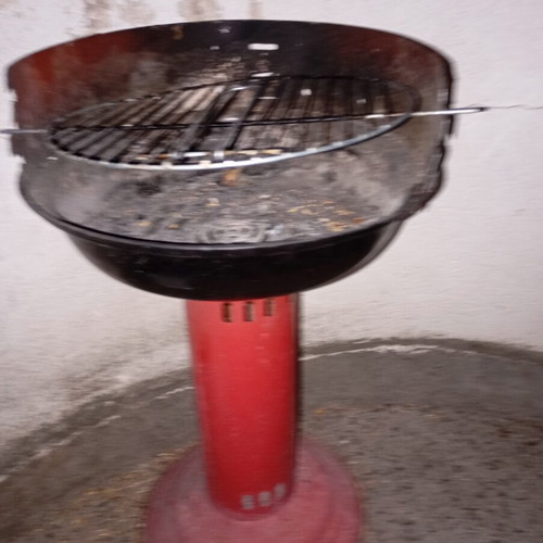 Portable vintage charcoal barbecue with red central leg, used