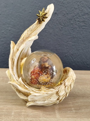 Christmas decorative snow globe featuring the Nativity and a base shaped like an angel's wing
