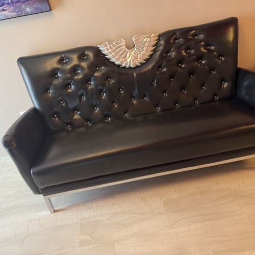 Black three-seater sofa with tufted back and metal base