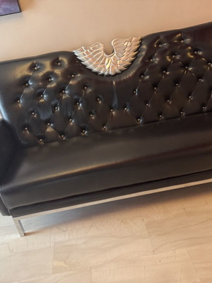 Black three-seater sofa with tufted back and metal base
