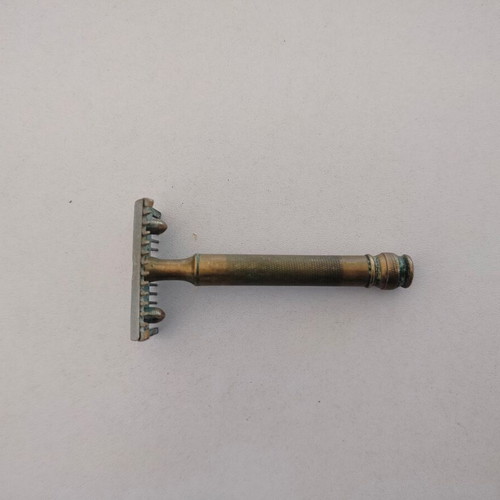 Vintage brass razor used with visible wear and oxidation