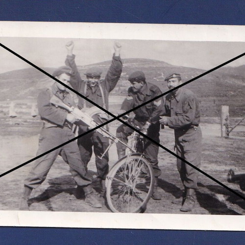 Photo of uniformed soldiers with weapons and officer with bicycle used