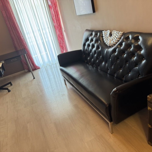 Black three-seater sofa with tufted back and metal base