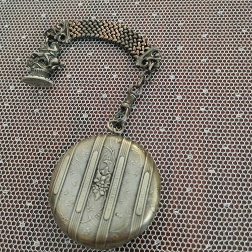 Silver powder compact used, 1880 era with chain and embossed figures