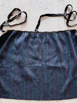 Traditional black apron with vertical stripes used