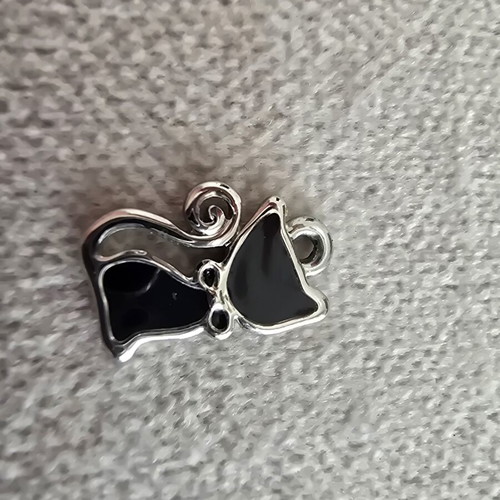 Metal cat charm with black enamel and silver details
