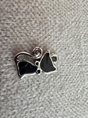 Metal cat charm with black enamel and silver details
