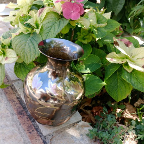 Intricately enameled brass vase with flowers.