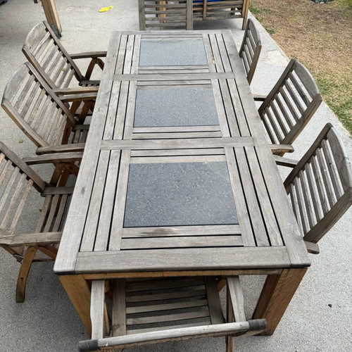 Outdoor table with 8 used teak chairs and black stone