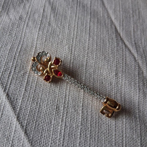 Metal key-shaped pin like new, multicolored, gold tone