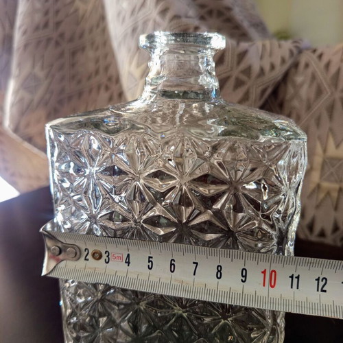 Vintage glass decanter with embossed geometric design and stopper