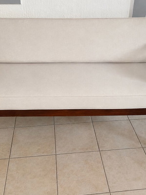 Wooden two-seater outdoor sofa with cream cushions