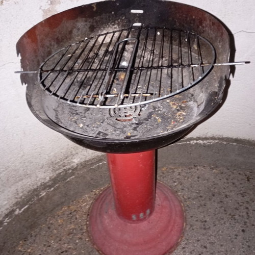 Portable vintage charcoal barbecue with red central leg, used