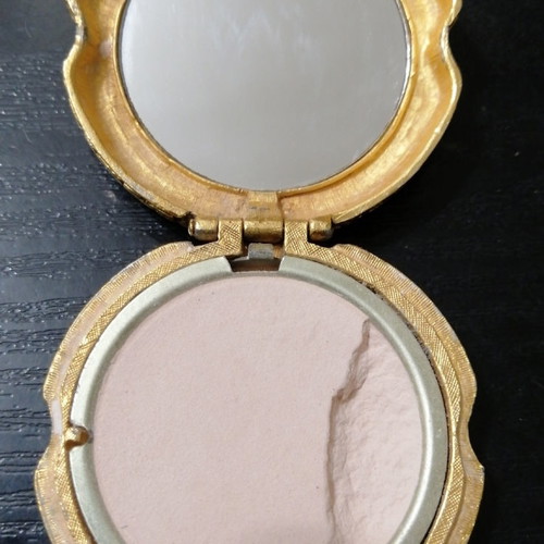 Vintage powder compact used with mirror and gold-plated box with emerald