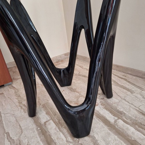 Oval dining table with tempered glass top and sculptural black base