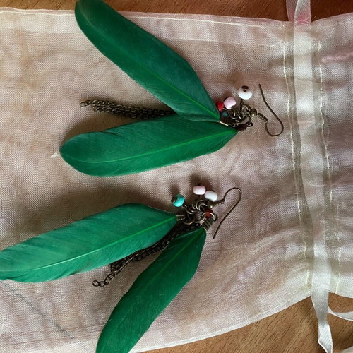 Handmade earrings used with green feathers and multicolored beads