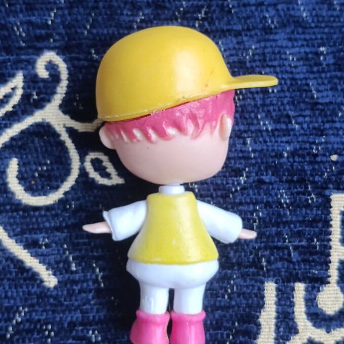 Doll figure with yellow cap and pink hair