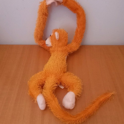 Stuffed monkey with scratches like new, orange color
