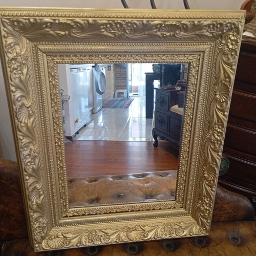 Baroque wall mirror with carved gold frame and embossed motifs