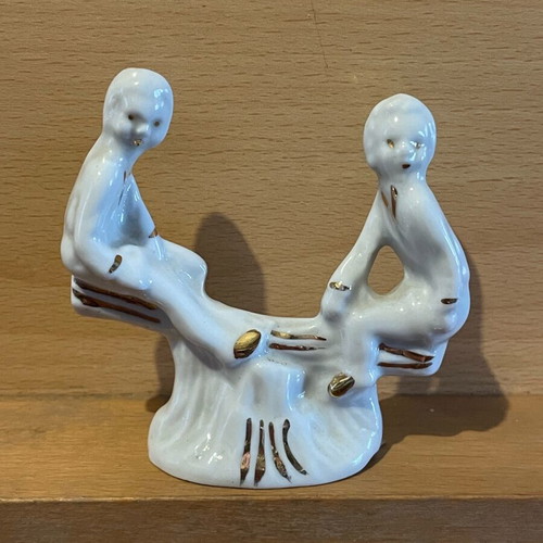 Porcelain children on seesaw gilded like new