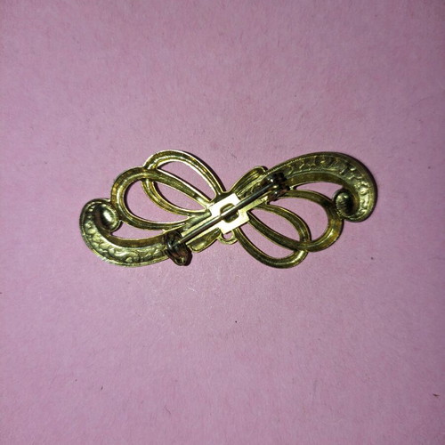 Bow-shaped pin new, gold color with green stones