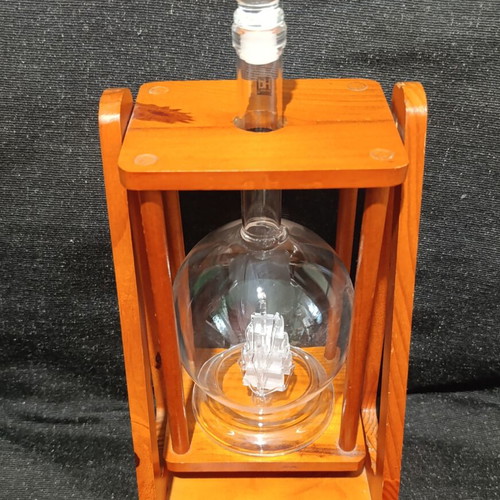 Vintage glass decanter with ship inside on wooden base, used