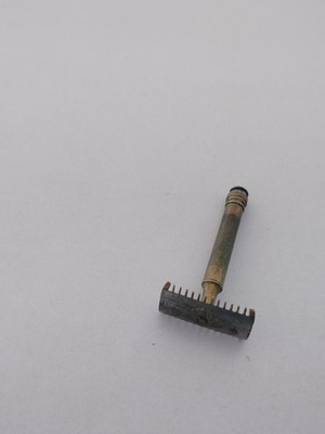 Vintage brass razor used with visible wear and oxidation