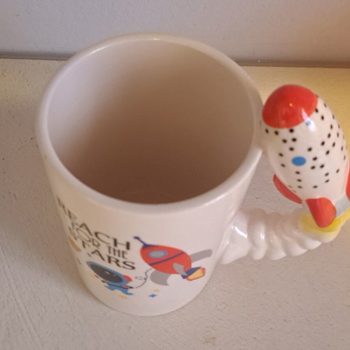 Ceramic space-themed mug with 3D rocket handle and Reach for the Stars phrase