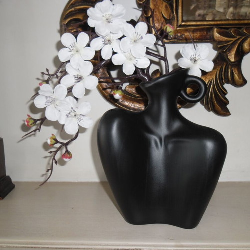 White orchid and black plastic vase shaped like female bust