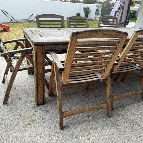 Outdoor table with 8 used teak chairs and black stone