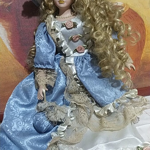 Porcelain Victorian-style doll with curly blonde hair and blue lace dress