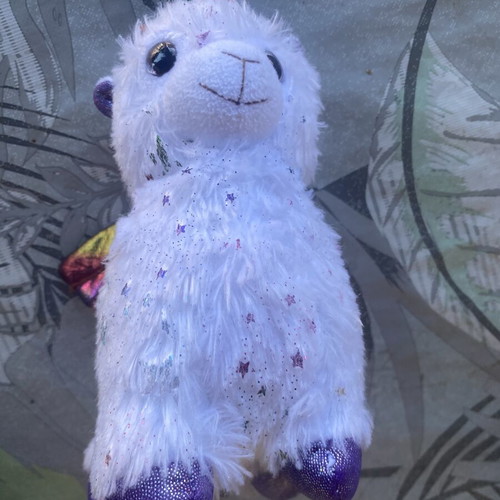 Unicorn plush toy with colorful shiny wings and metallic purple details